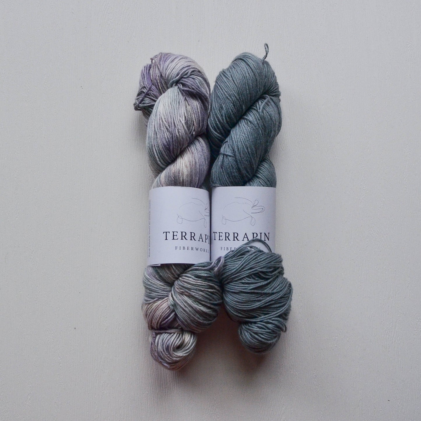 Two skeins of yarn with labels on a light gray background