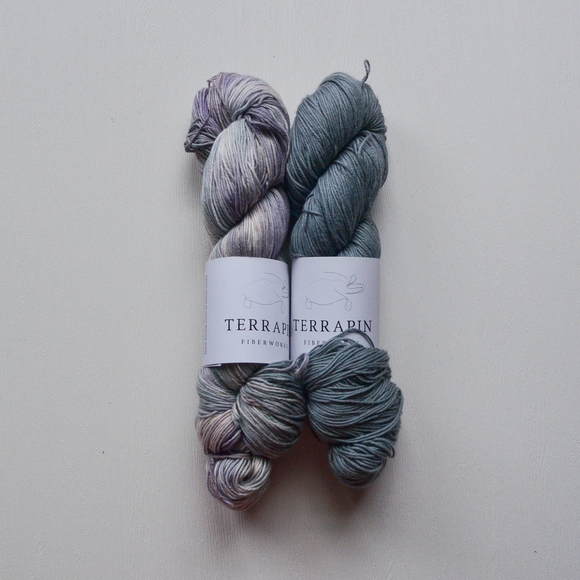 Two skeins of yarn with labels on a light gray background